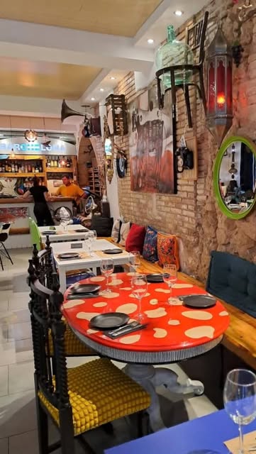 La sala amb taules pintades, miralls de colors, fanalets i la barra al fons